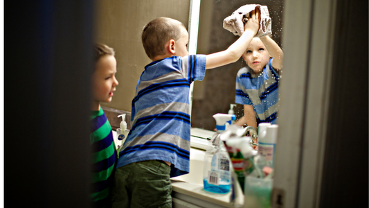 Young boy using a cloth to clean the window with minq glass cleaner solution